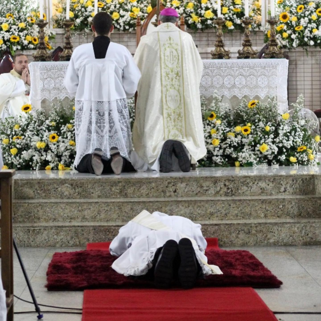 Fr. Thiago prostrate during Ordination while Bishop da Cunha kneels in prayer